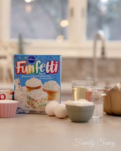 a box of funfetti frosting next to cupcakes and other ingredients