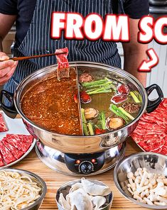 a person holding chopsticks in front of a large pot filled with meat and vegetables