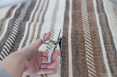 someone is cutting fabric with scissors on a tablecloth that has brown and white stripes