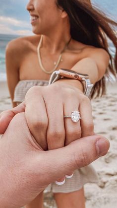 a woman holding the hand of a man with a diamond ring on his left finger