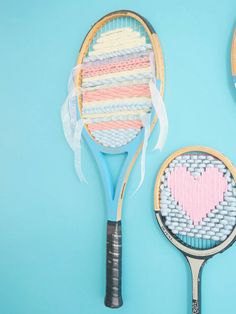 two tennis racquets decorated with hearts and ribbons on a blue background next to each other