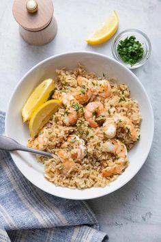 shrimp and rice in a bowl with lemon wedges