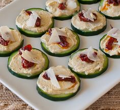 cucumbers with cream cheese and jelly on them sitting on a white platter