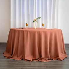 two vases with flowers are on top of a table in front of a curtain