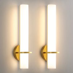 two lights that are next to each other on a wall in front of a white wall