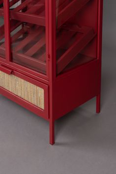 a red cabinet with wicker drawers on the top and bottom, against a gray background