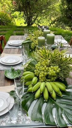 the table is set with green and white plates, silverware, and fruit on it