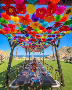 an outdoor dining area with colorful paper flowers on the ceiling and tables set for dinner