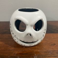 a white ceramic mask with black eyes on a wooden table