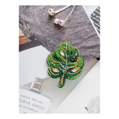 a green brooch sitting on top of a table next to earphones and other items