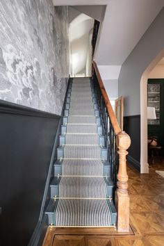 the stairs are lined with black and white striped carpet, along with wooden handrails