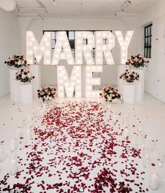 a large sign that says marry me surrounded by candles and flowers