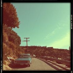 an old car is parked on the side of the road in front of a telephone pole