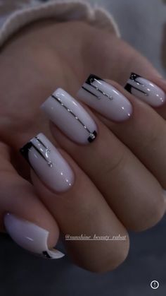 a woman's hand with white and black nail polishes on her nails,