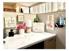 a white counter top sitting under a window next to a lamp and pictures on the wall