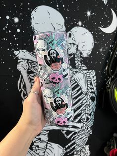 a person holding up a cell phone case with skulls on it