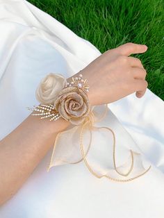 a woman's hand wearing a white dress with a flower and pearls on it