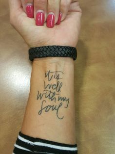 a woman's arm with writing on it and a black braided wristband