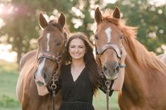 a woman standing next to two brown horses