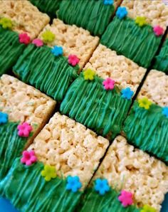 rice krispy treats with green frosting and colorful flowers on them are arranged in rows