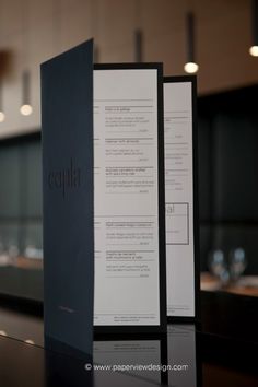 two menus sitting on top of a black table