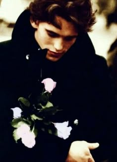 a young man is holding a rose in his hand