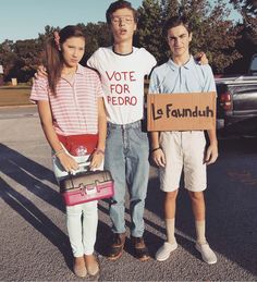 three people standing next to each other holding signs