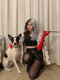 a woman sitting on the floor next to a dog and holding a red object in her hand