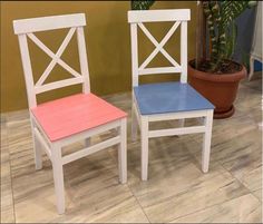 two wooden chairs with different colored seats on top of each other in front of a potted plant