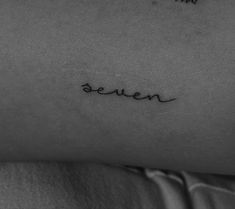 a small tattoo that says queen on the back of a woman's stomach and is written in cursive font