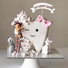 a tooth shaped cake on top of a white plate with a girl and boy figurines