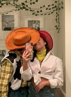 two people wearing cowboy hats are taking a selfie with a cell phone in front of them