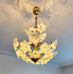 a chandelier with white flowers hanging from the ceiling