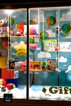 there is a display case with toys in the window and clouds on the wall behind it