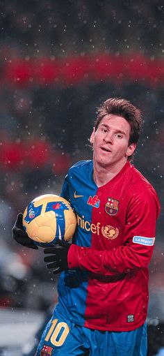 a man holding a soccer ball in the rain