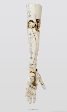 an artificial hand is holding something in it's right hand, with gold and white designs on the fingers