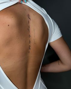 the back of a woman's white shirt with writing on her left shoulder and right arm