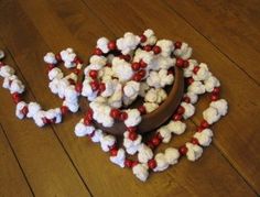 a bowl filled with marshmallows on top of a wooden floor next to red and white beads