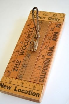 a wooden ruler with a pair of scissors on it and the words new location printed on it