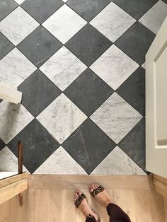 a person standing in front of a black and white checkered wall with their feet on the floor