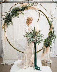 a woman standing in front of a circular arch with greenery and flowers on it