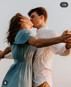 a man and woman kissing each other while standing next to each other with their hands in the air