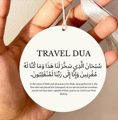 a hand holding a tag with the words travel dua written in arabic and english