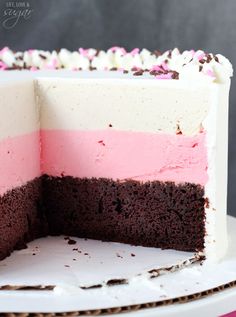 a cake with pink, white and chocolate frosting is cut in half on a plate