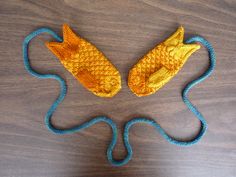 two knitted fish shaped objects sitting on top of a wooden table