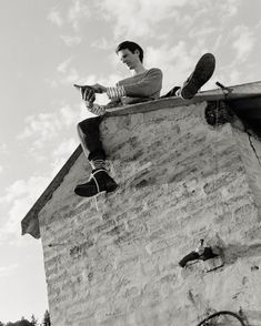 a man sitting on top of a brick building