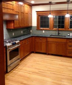 an empty kitchen with wood cabinets and stainless steel stove top oven in the center, surrounded by hardwood flooring