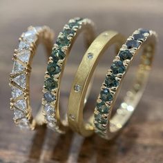 three gold rings with green and white diamonds