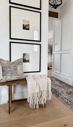 a wooden bench sitting in the middle of a room with pictures hanging on the wall