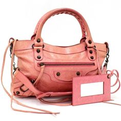 This Is An Authentic Balenciaga Agneau Leather Classic First In Pink. This Stylish Tote Is Crafted Of Beautifully Textured Agneau Lambskin Leather. The Handbag Features Rolled Leather Top Handles With A Woven Detail, An Optional Shoulder Strap, A Facing Zipper Pocket, Belts And Aged Brass Buckles And Studs. The Top Zipper Opens To A Black Fabric Interior With A Zipper Pocket. This Bag Has Room For All Of Your Day Or Evening Essentials With The Forward Fashion Only From Balenciaga! Length: 13.25 In Width: 2.50 In Height: 7.00 In Drop: 3.75 In Condition Notes: Good Condition. Minor Hardware And Leather Wear. Please Refer To All Photos As They Are Part Of The Description. We Ship Daily Leather Wear, Balenciaga Bag, Brass Buckle, One Bag, Leather Top, Lambskin Leather, Black Fabric, Leather Handle, Leather Fashion